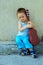 Cute baby boy with guitar sitting against wall