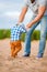 Cute baby boy learns to walk holding daddy`s hands on the beach on the sand