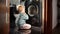 Cute baby boy looking at washing machine doing laundry. Doing housework and chores, children education and development.