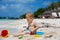 Cute baby boy playing with beach toys on tropical beach