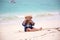 Cute baby boy playing with beach toys on tropical beach