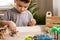 Cute baby boy playing sensory box kinetic sand table with carnivorous and herbivorous dinosaurs