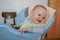 Cute baby boy sitting on the baby chair and waiting dinner.