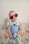Cute baby boy in sunglasses playing with money, hundreds of dollars