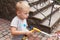 Cute baby boy waters the flowers on the back yard, mother assistant.