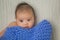 Cute baby covered in blue towel quilt making various expressions