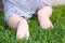 Cute baby crawling on green grass. Rear view. Primary focus on baby feet.
