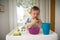 Cute baby eating first solid food, infant sitting in high chair.