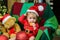 Cute baby face in Santa hat near Christmas tree tasting christmas sweet treats. Happy Childhood, child 1 year old. New