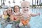 Cute baby with family smiling in swimming pool