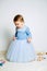 Cute baby girl in blue princess dress playing with toys at home. Kids dresses for prom and birthday holiday