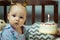 Cute baby girl celebrates 6th month from the birth. Happy little girl gets cake with candle.