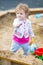 Cute baby girl digging in sand on a playground