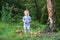 Cute baby girl gathering mushrooms in forest