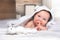 Cute baby girl in a hooded towel lying on the bed