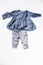 Cute baby girl outfit - denim top with ruffles and long sleeves and grey pants with ruffles - flat lay on white