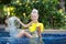 Cute baby girl in the pool. Little girl splashes in the pool of a tropical resort. The concept of tourism and beach holidays