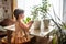 A cute baby girl takes care of houseplants. Girl watering and spraying indoor plants at home