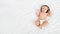Cute baby with headphones lying on white bed