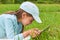 Cute baby lies on grass and plays computer