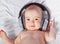 Cute baby listens to music through headphones.