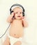 Cute baby listens to music in headphones lying on bed