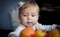 Cute baby looks on juicy red apples. Little girl reaching out for an apple