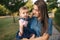 Cute baby on mom`s hands outside. Family in the park in summer. Denim style. Mom and daughter in jeans