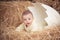 Cute baby newborn child posing in huge broken egg on dry straw in unique studio design decoration