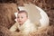Cute baby newborn child posing in huge broken egg on dry straw in unique studio design decoration