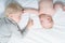 Cute baby and older brother interact while lying on the bed. Top view