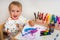 Cute baby is painting with paintbrush on paper