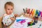 Cute baby is painting with paintbrush on paper