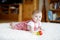 Cute baby playing with colorful rattle education toy. Lttle girl looking at the camera and crawling. Family, new life