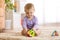 Cute baby playing with colorful toys sitting on carpet in white sunny bedroom. Child with educational toy. Early