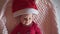 Cute Baby Santa lying in a suit of Santa Claus, in a red hat, red pajamas. Volunteer baby Santa. Camera down