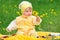 Cute baby sitting in grassy field with dandelions