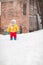 Cute baby in thermal clothes standing and playing in the snow