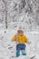 Cute baby in thermal clothes standing and playing in the snow