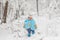 Cute baby in thermal clothes standing and playing in the snow