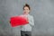 Cute baby thoughtful girl with hands shaped with red rectangle. Gray background.