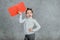 Cute baby thoughtful girl with hands shaped with red rectangle. Gray background.