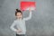 Cute baby thoughtful girl with hands shaped with red rectangle. Gray background.