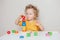 Cute baby toddler playing with learning toy pyramid stacking blocks at home or kindergarten. Early age education. Kids hand brain