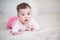 Cute baby under 1 year old with surprised expression wearing pajamas crawling in bed at home close up. Childhood.