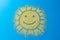 Cute background. Confectionery sprinkles shape of the sun with a smile. Yellow sugar grains on a blue color.