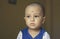 Cute bald indian baby boy in blue and white shirt looking away. Head and shoulder shot. Close up