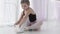 Cute ballet dancer tying ballet shoes before training