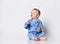 Cute barefooted blond baby boy toddler in blue fleece jumpsuit with stars sits on the floor looking up with opened mouth