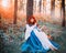 Cute Bavarian beauty under tree in morning light forest with basket of apples